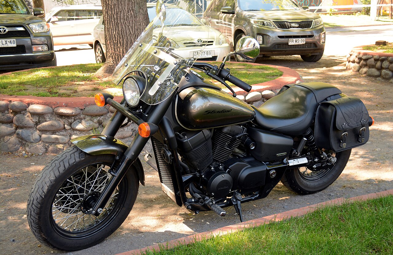 Honda Shadow cruiser with windscreen and saddlebags parked beside a lawn